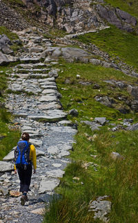 Woman with rucksack hiking up rocky path