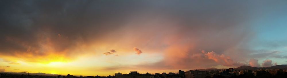 Silhouette of cityscape against cloudy sky during sunset