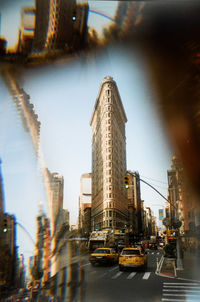 Traffic on city street by buildings against sky