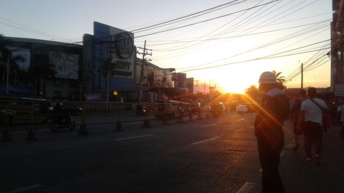 People walking on road in city at sunset