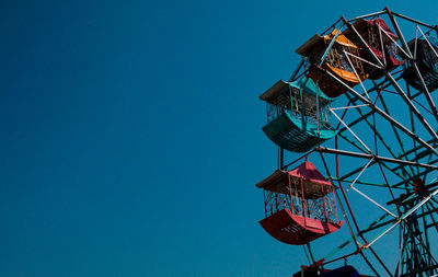 Low angle view of ferris wheel against blue sky