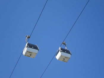 Low angle view of power lines against clear blue sky