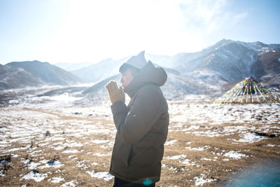 Side view of man standing on snow covered land