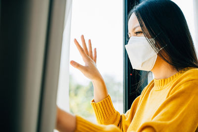 Side view of woman looking through window