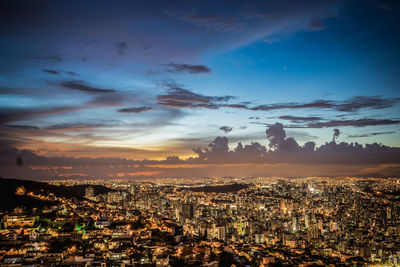 High angle view of illuminated city buildings against sky at sunset