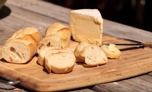 High angle view of baguette and brie cheese with knife on cutting board