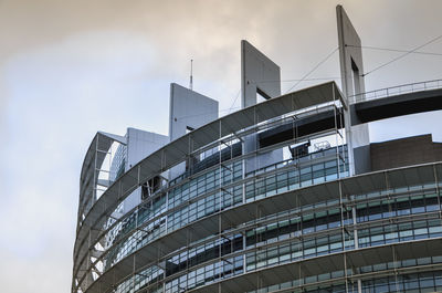 Low angle view of modern building against cloudy sky