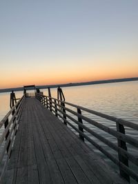 Pier over sea against sky during sunset