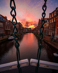 Canal amidst buildings against sky during sunset