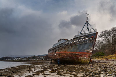 Abandoned boat in sea against sky