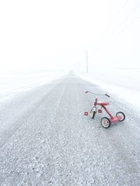 Bicycle on road against sky during winter