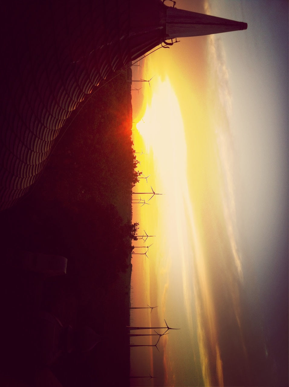 sunset, silhouette, sky, landscape, sun, scenics, field, tranquil scene, rural scene, beauty in nature, tranquility, nature, transportation, orange color, fuel and power generation, cloud - sky, mode of transport, dusk, no people, outdoors