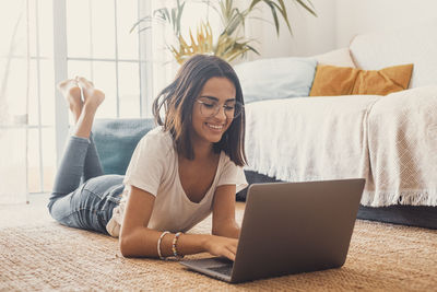 Woman using laptop lying on floor at home