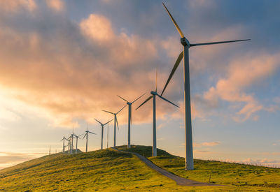 Windmill on field against sky during sunset