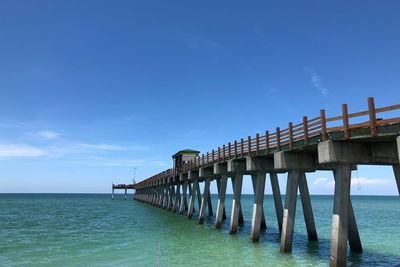 Pier over sea against blue sky