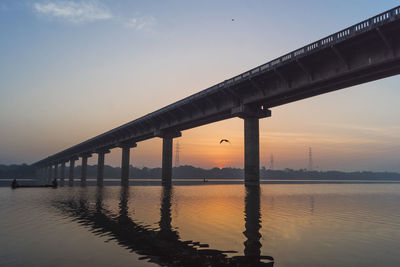 Bridge over river against sky during sunset