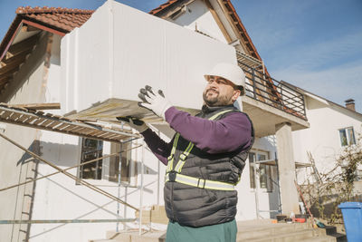 Construction worker walking with polystyrene foam on sunny day