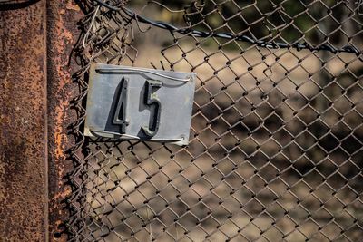 Close-up of arrow symbol on chainlink fence