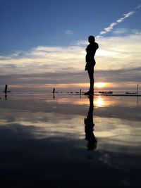 Silhouette man standing on beach against sky during sunset