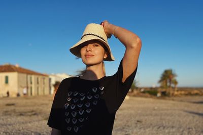 Portrait of young woman standing against sky