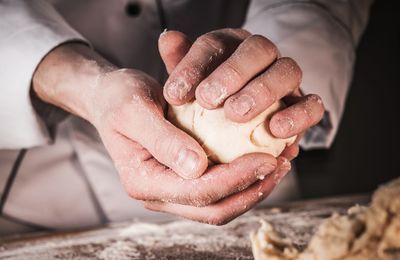 Midsection of chef kneading dough on table