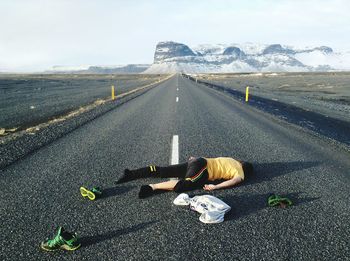 Man lying on country road along landscape