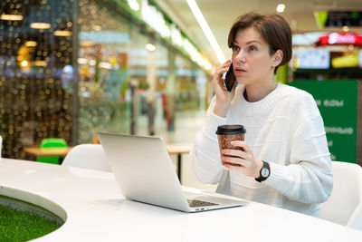 Serious woman talking on phone in shopping mall