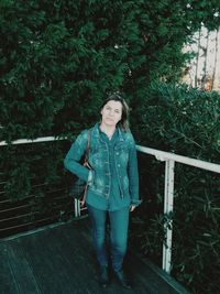 Portrait of woman standing against railing