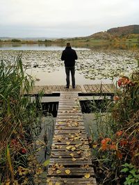 Rear view of man standing on lake against sky