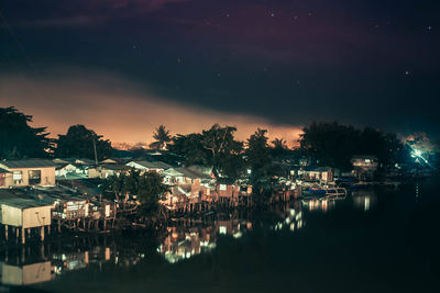 Illuminated town against sky at night