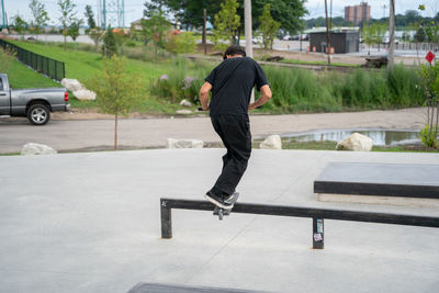 Rear view of man skateboarding on city street