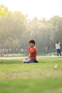 Boy kneeling on grassy land in park