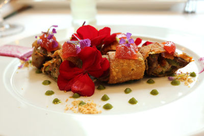 Close-up of flowers on spring rolls with meat in plate