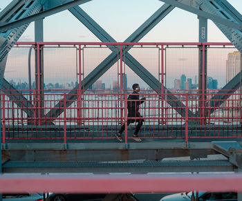 Side view of man running on bridge during sunset