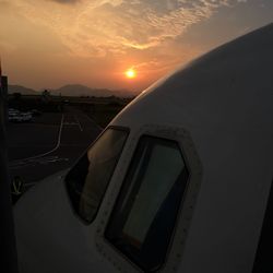 Close-up of airplane wing against sky during sunset