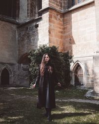 Woman long hair witch in black standing in front of the castle with her magic wond looking dangerous