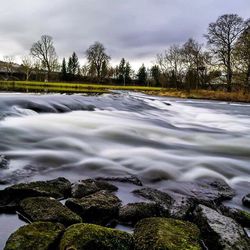 Scenic view of river against cloudy sky