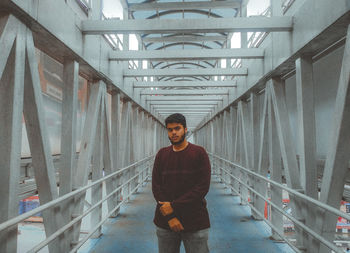 Portrait of young man standing on railing against building