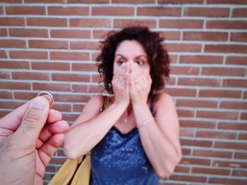 Male hand holds out the ring as a marriage proposal and the girl is amazed and happy