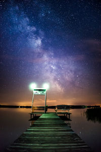 Jetty over lake against sky at night