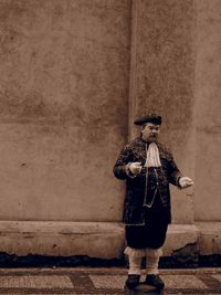 Full length portrait of a man standing against wall