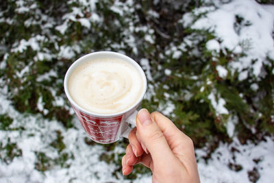 Hand holding coffee cup during winter