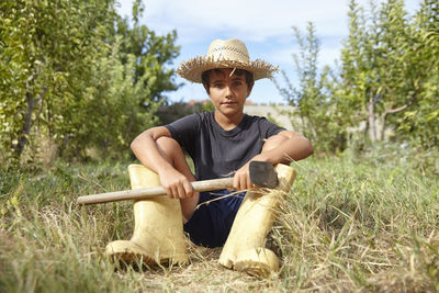 Portrait of a child sitting in the field wearing a straw hat