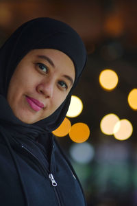 Portrait of indonesian muslim woman wearing black hijab with bokeh.