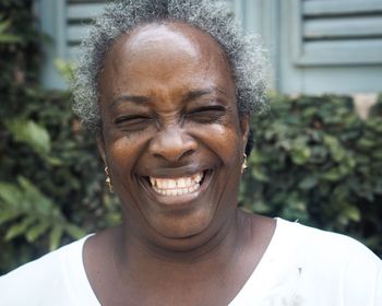 Close-up of mature woman laughing against plants