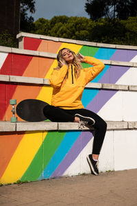 Portrait of a cheerful woman with a skateboard on colorful stairs