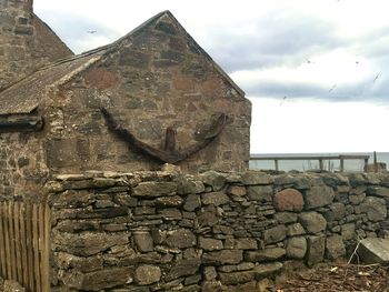 Stone wall of old building against sky