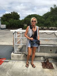 Mature woman standing with camera by railing