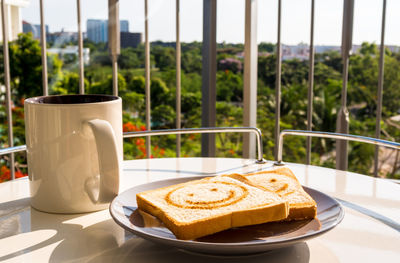 The cup of coffee and some bread breakfast with morning light at the balcony