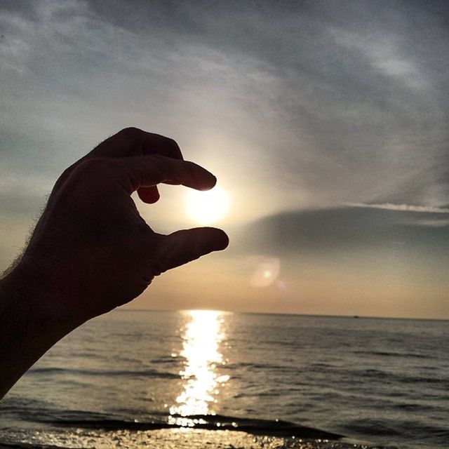 sea, water, horizon over water, sky, sunset, person, part of, sun, silhouette, holding, cropped, unrecognizable person, lifestyles, beauty in nature, leisure activity, scenics, human finger